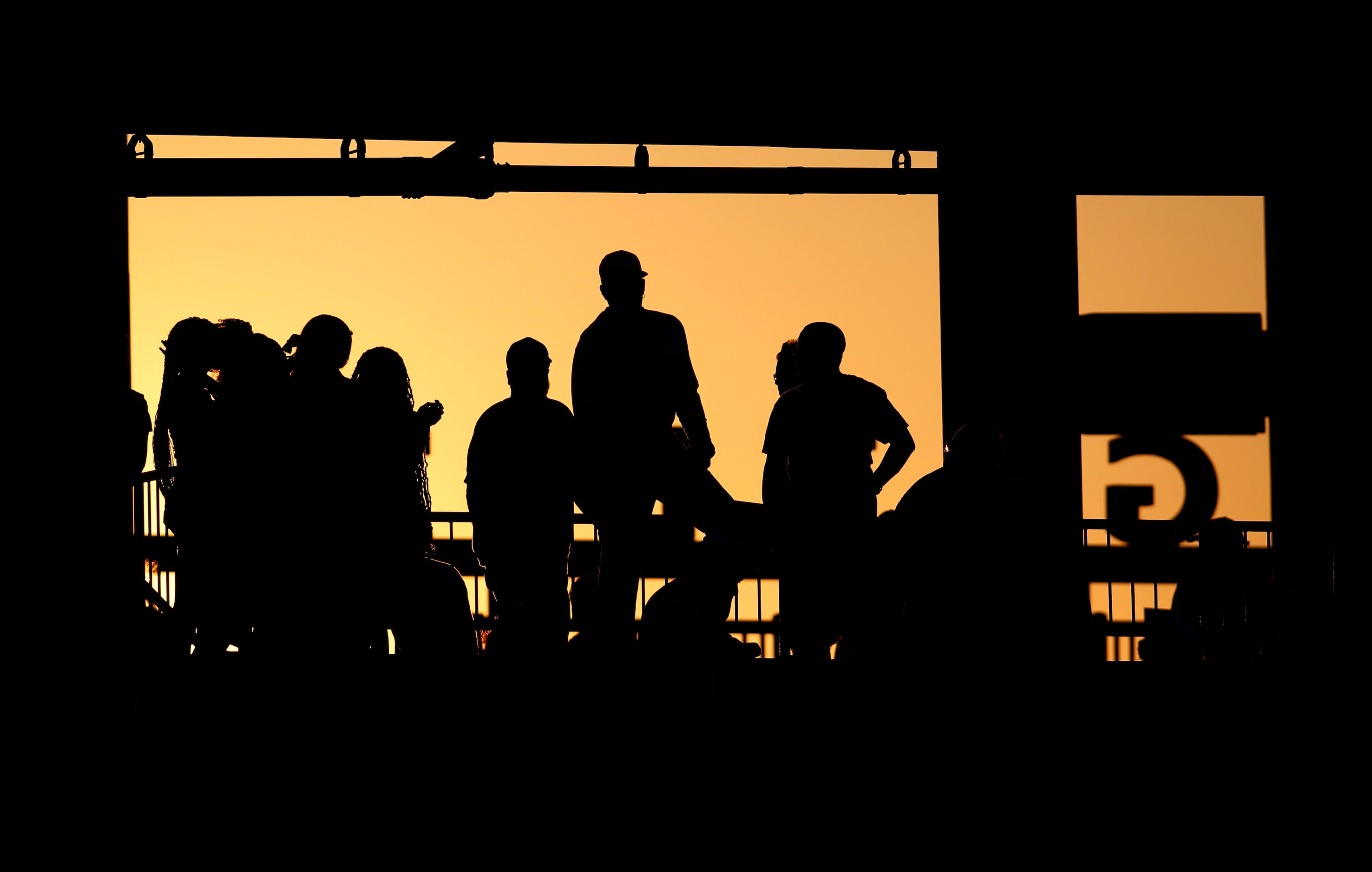 Fans on the home side of the stands are silhouetted against a setting sun prior to the...