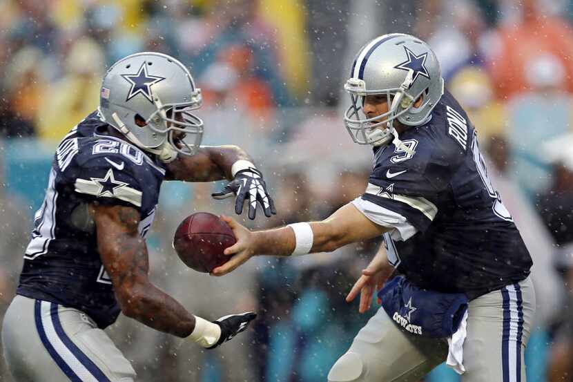 Dallas Cowboys quarterback Tony Romo (9) makes a handoff to running back Darren McFadden...