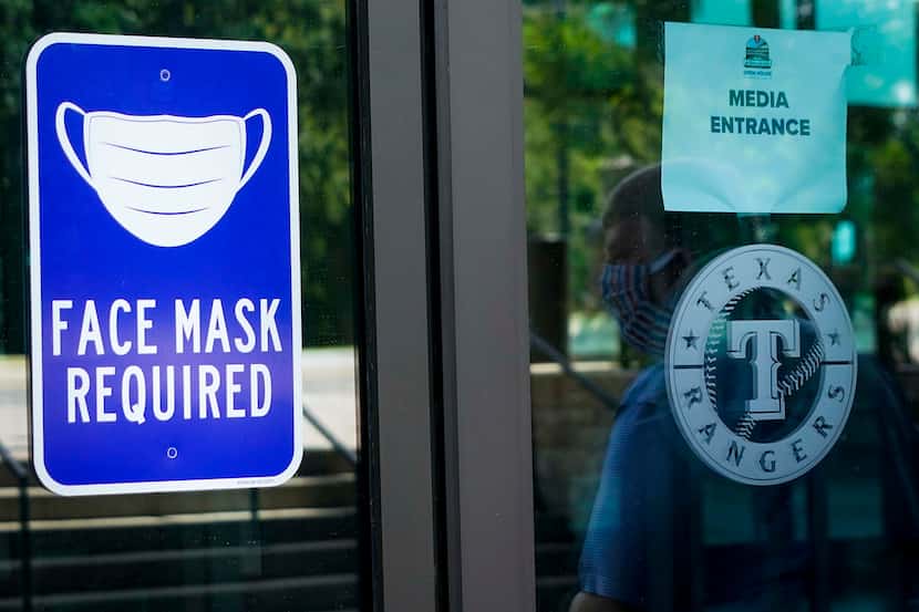 A sign outside indicates the face mask requirement during the Texas Rangers first Summer...