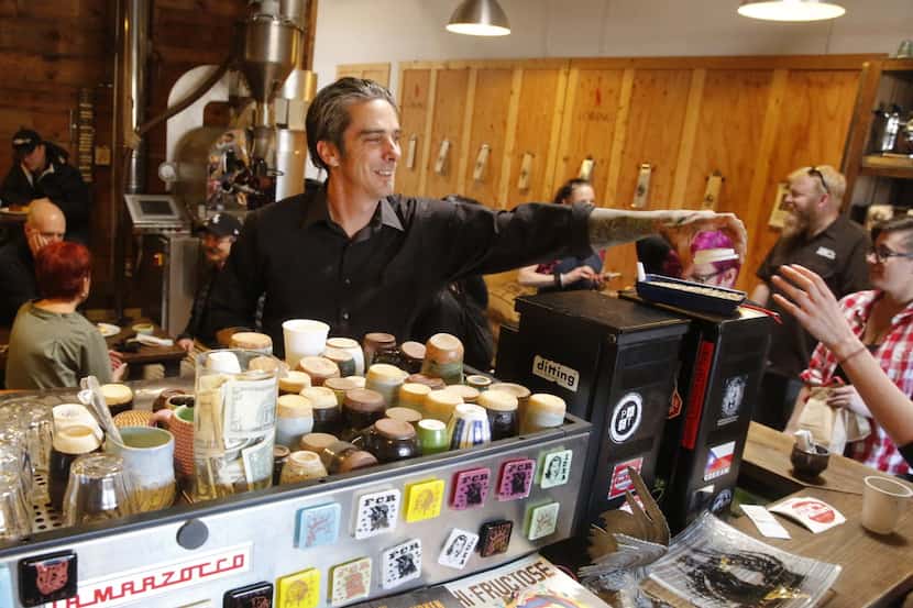 Michael Wyatt, center in black, owner of Full City Rooster, hands a coffee cup lid to a...