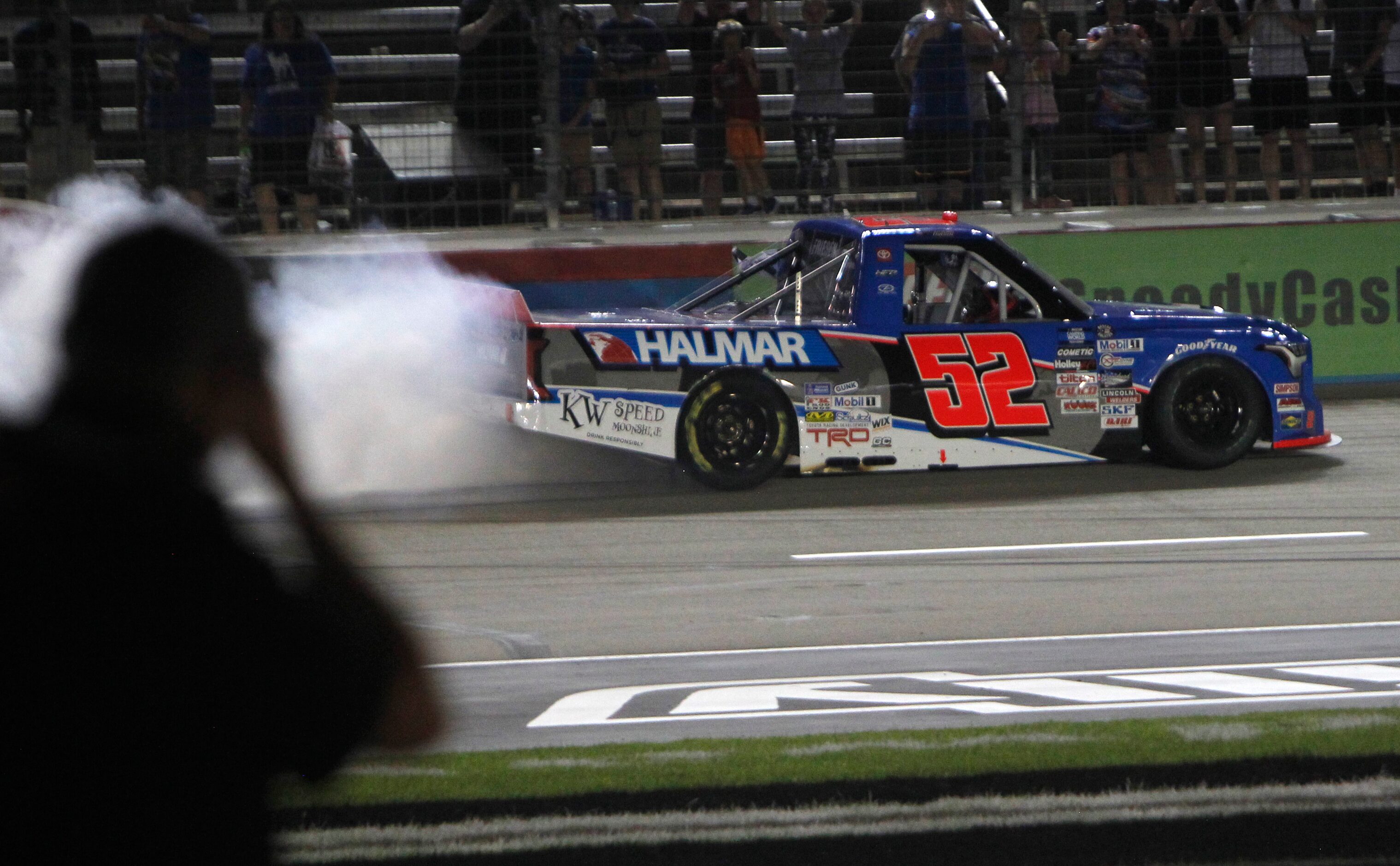 A photographer on the infield photographs Stewart Friesen in the Halmar International Toyota...