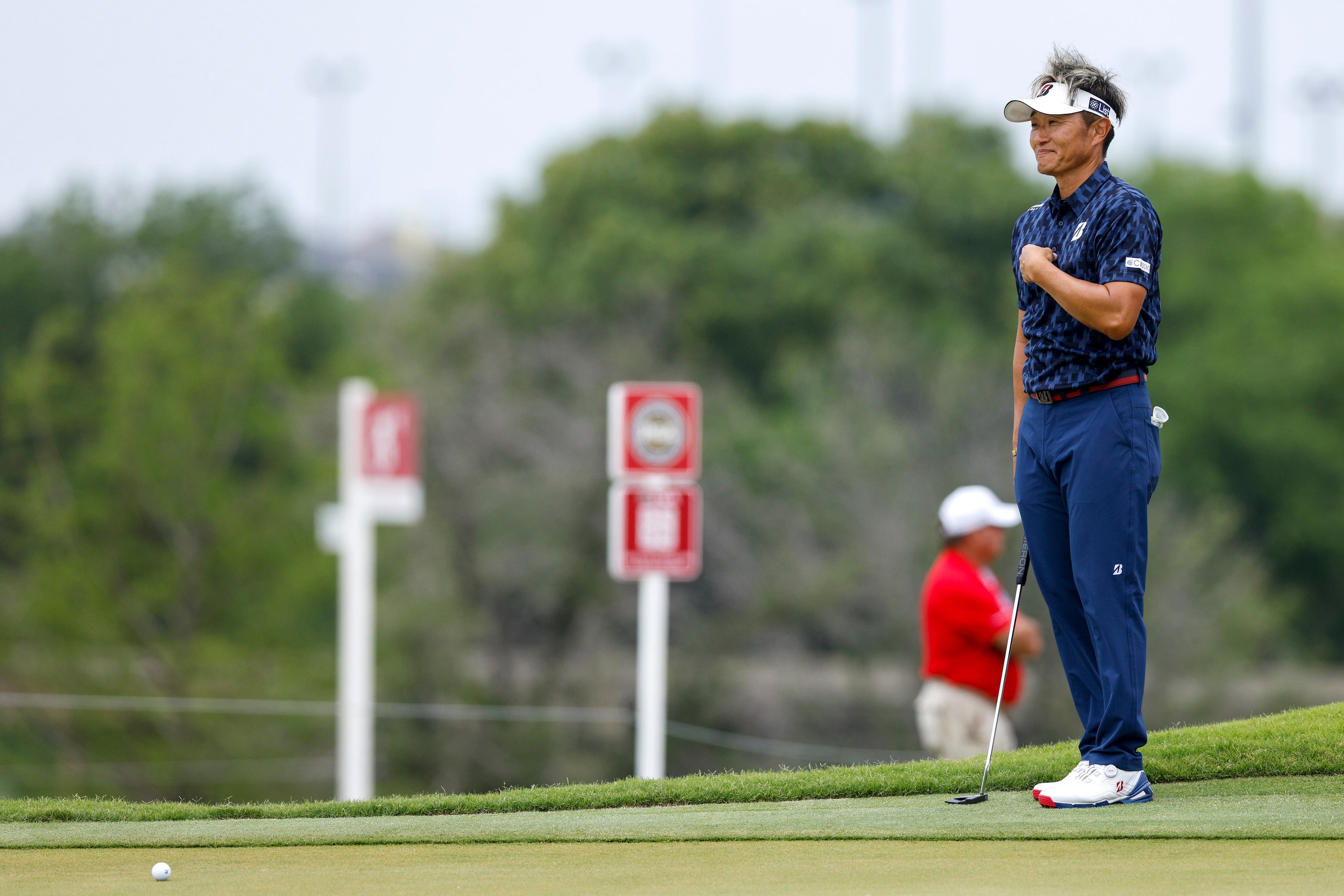 Katsumasa Miyamoto of Japan points to himself as he talks with his caddie on the ninth green...