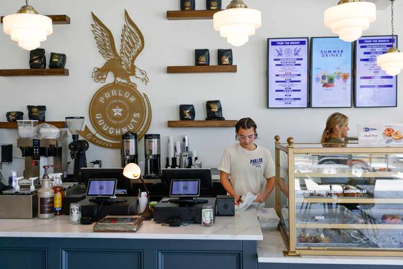 Parlor Doughnuts employees Faith Ferren (center) and  Ashlynne Newton work by the front...