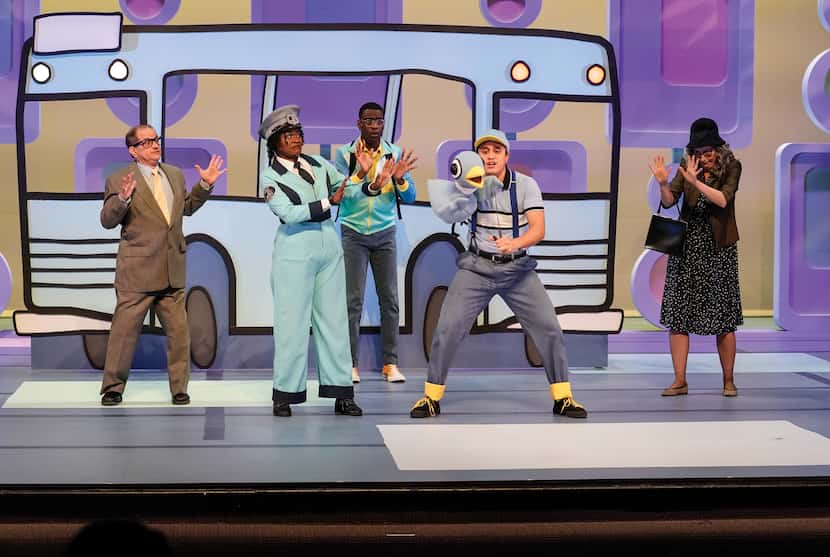 Five actors in costume perform on stage at a children’s theater in front of a blue bus backdrop