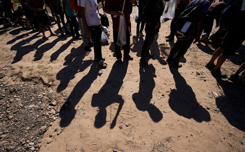 Migrants wait to be processed by the U.S. Customs and Border Patrol after they crossed the...