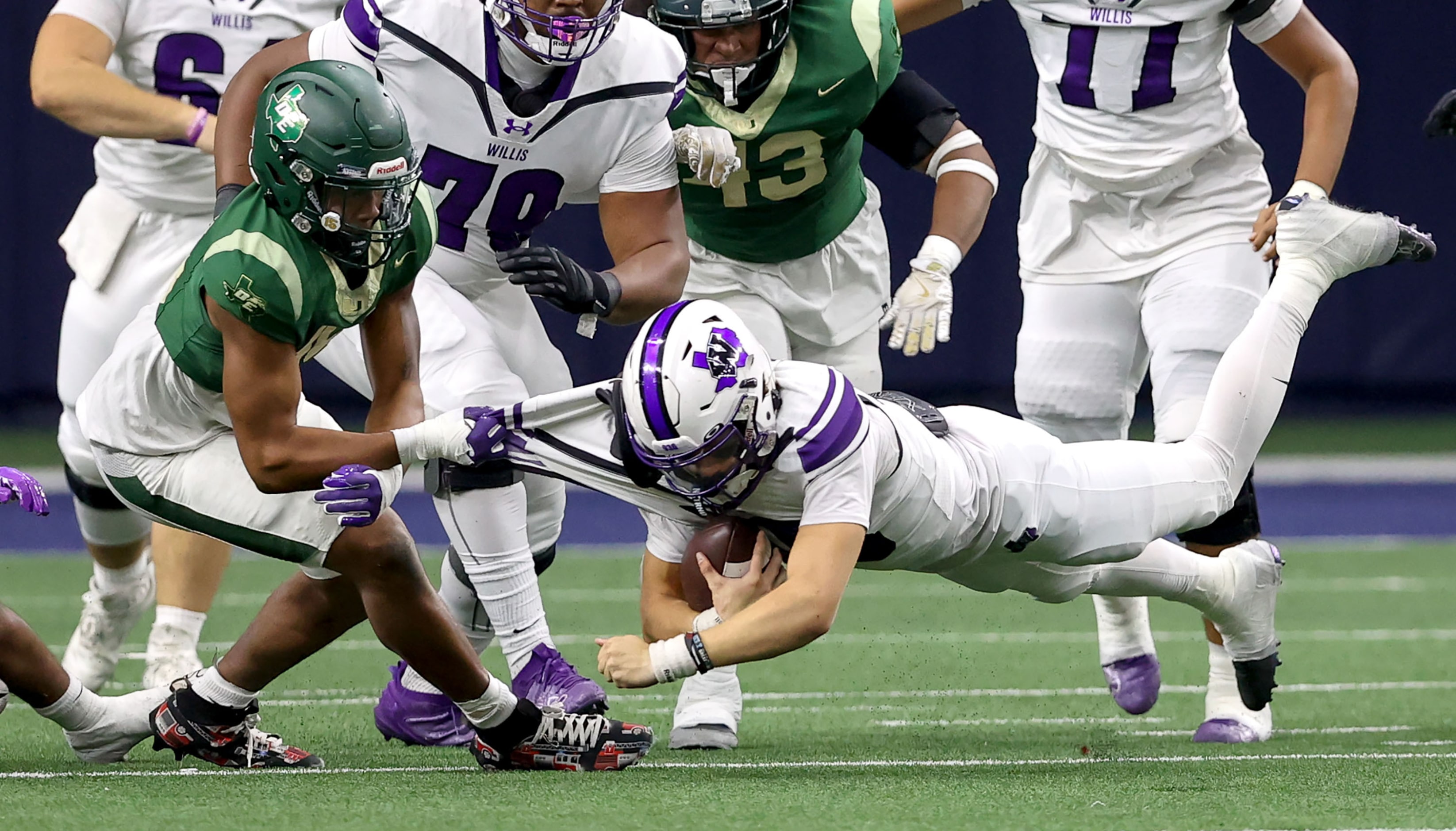 Willis quarterback Jack Emerson (right) is pulled down for a short gain by DeSoto defensive...