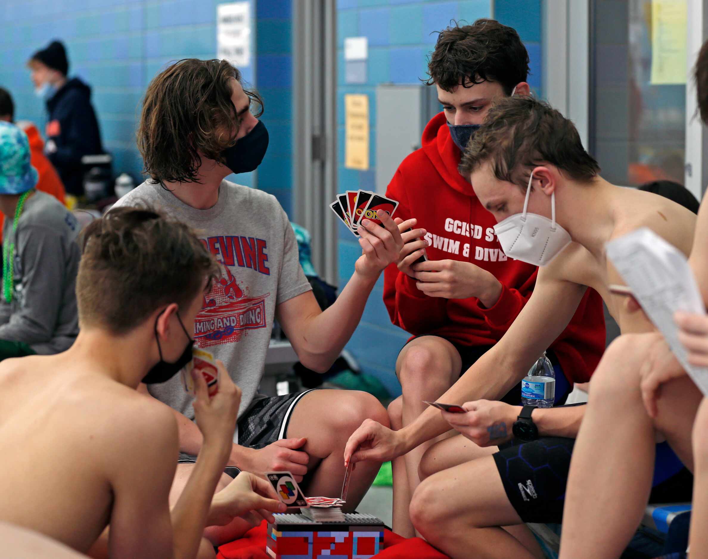 Grapevine HS swimmers pass the time waiting for competition to begin by playing cards. UIL...