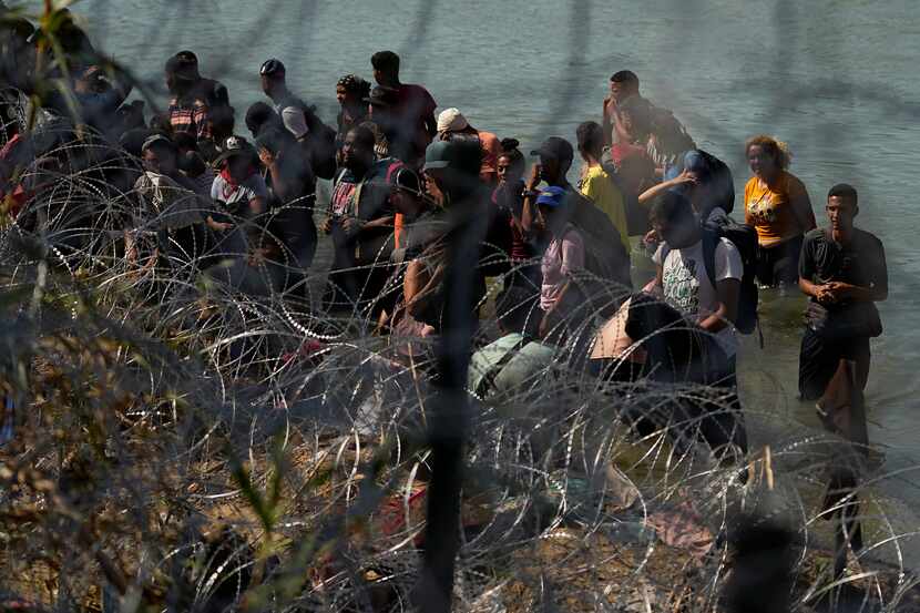 Migrants who crossed into the U.S. from Mexico are met with concertina wire along the Rio...