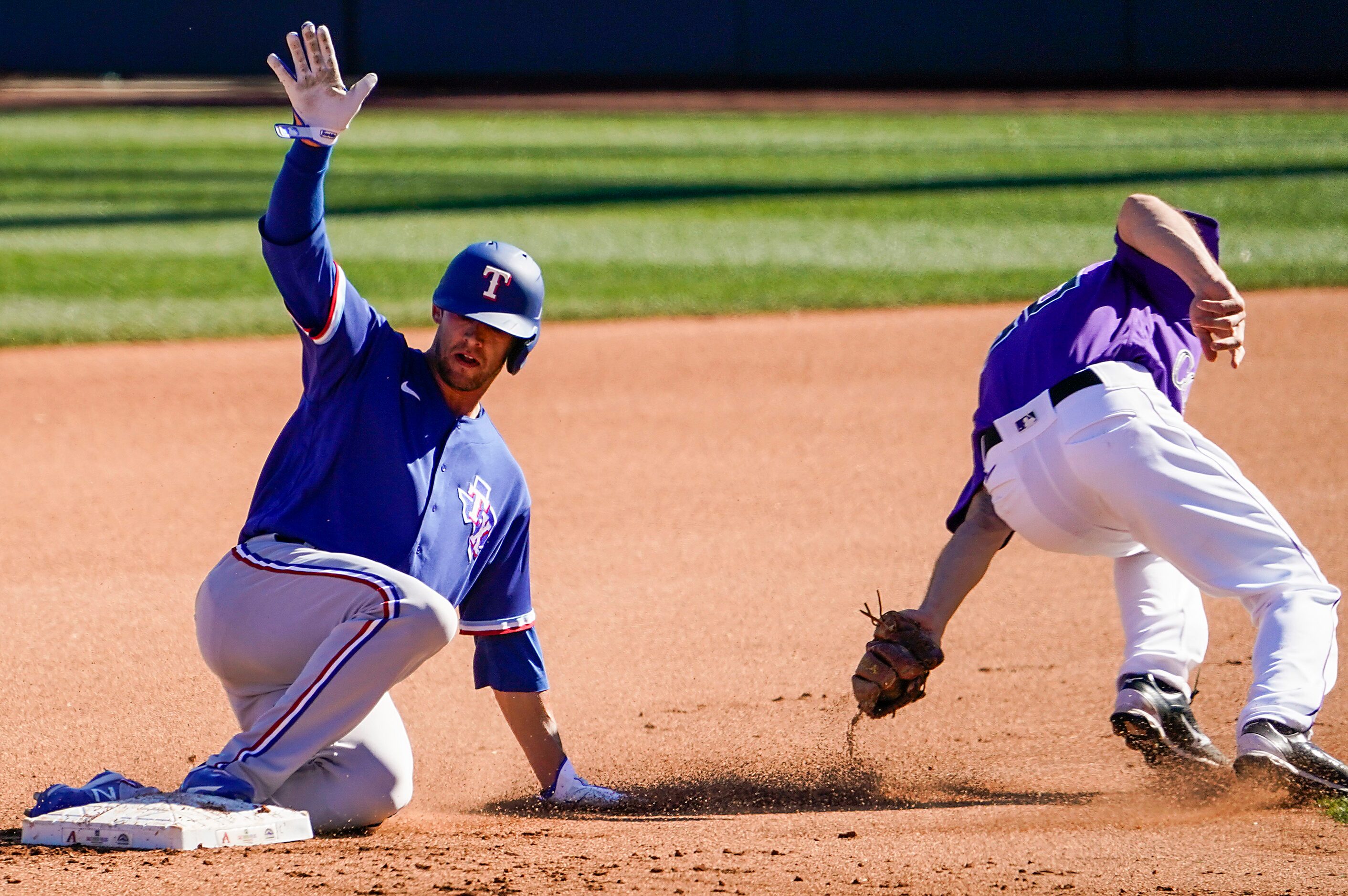 Texas Rangers infielder Eli White slides past the tag of Colorado Rockies second baseman...