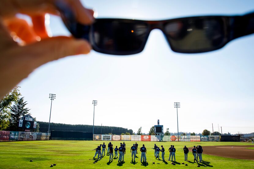 The first stages of a total solar eclipse are seen through eclipse glasses as players warm...