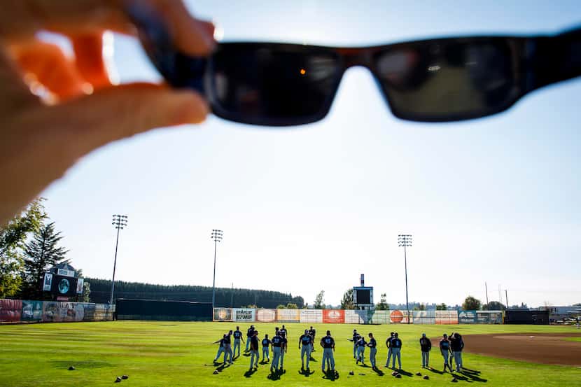The first stages of a total solar eclipse are seen through eclipse glasses as players warm...