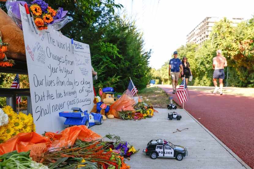 Pedestrians pass by a plaque dedicated to former Dallas police Chief David Kunkle on...