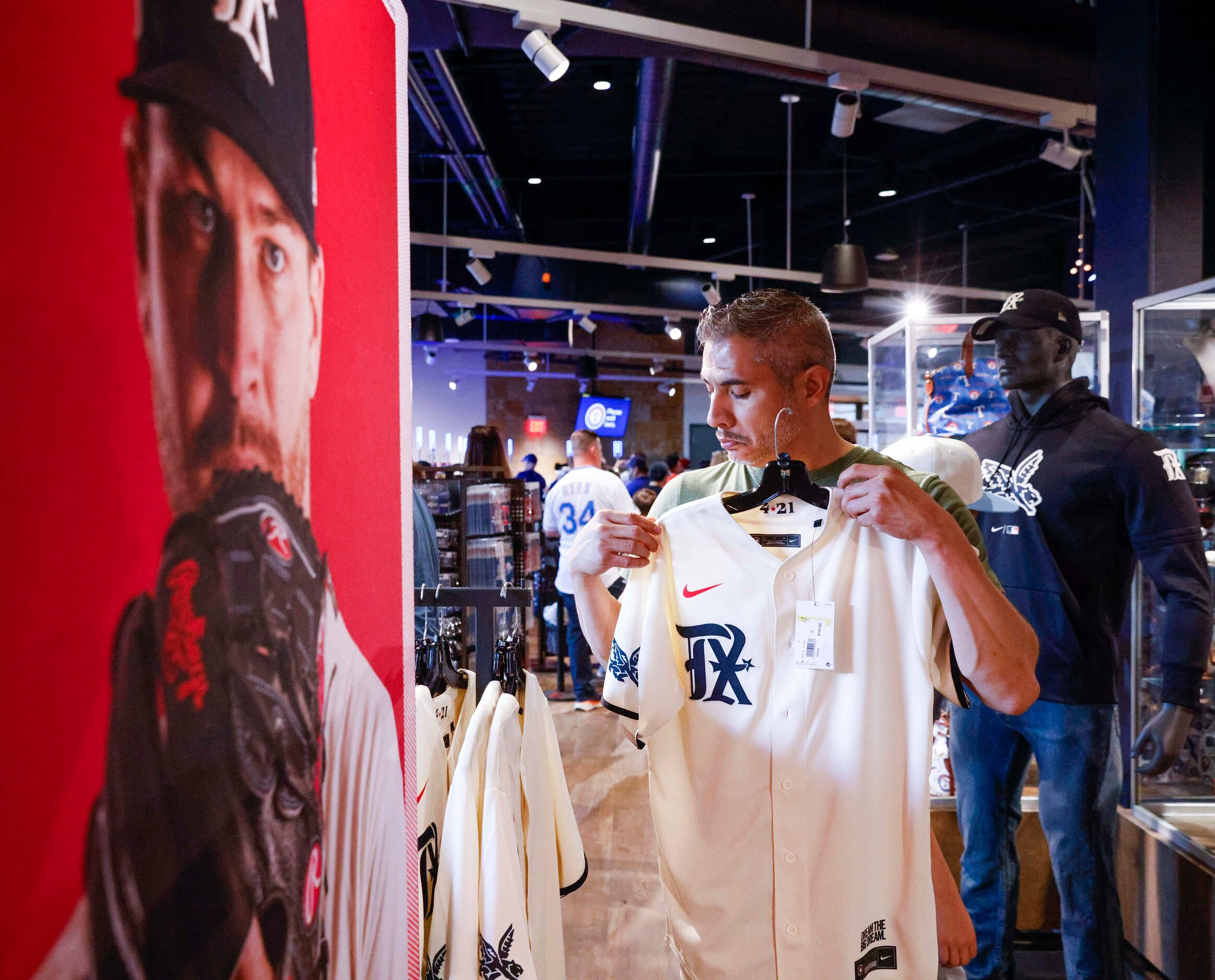 Ro Rives of Dallas area tries a Texas Rangers City Connect jersey before a baseball game...