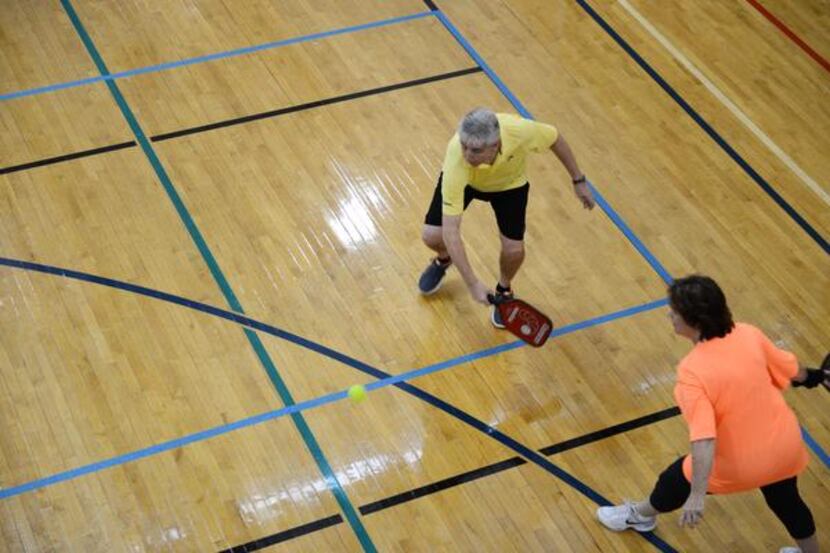 
Michael Dalby and Linda Lightfoot run to paddle the ball across the court during a round of...