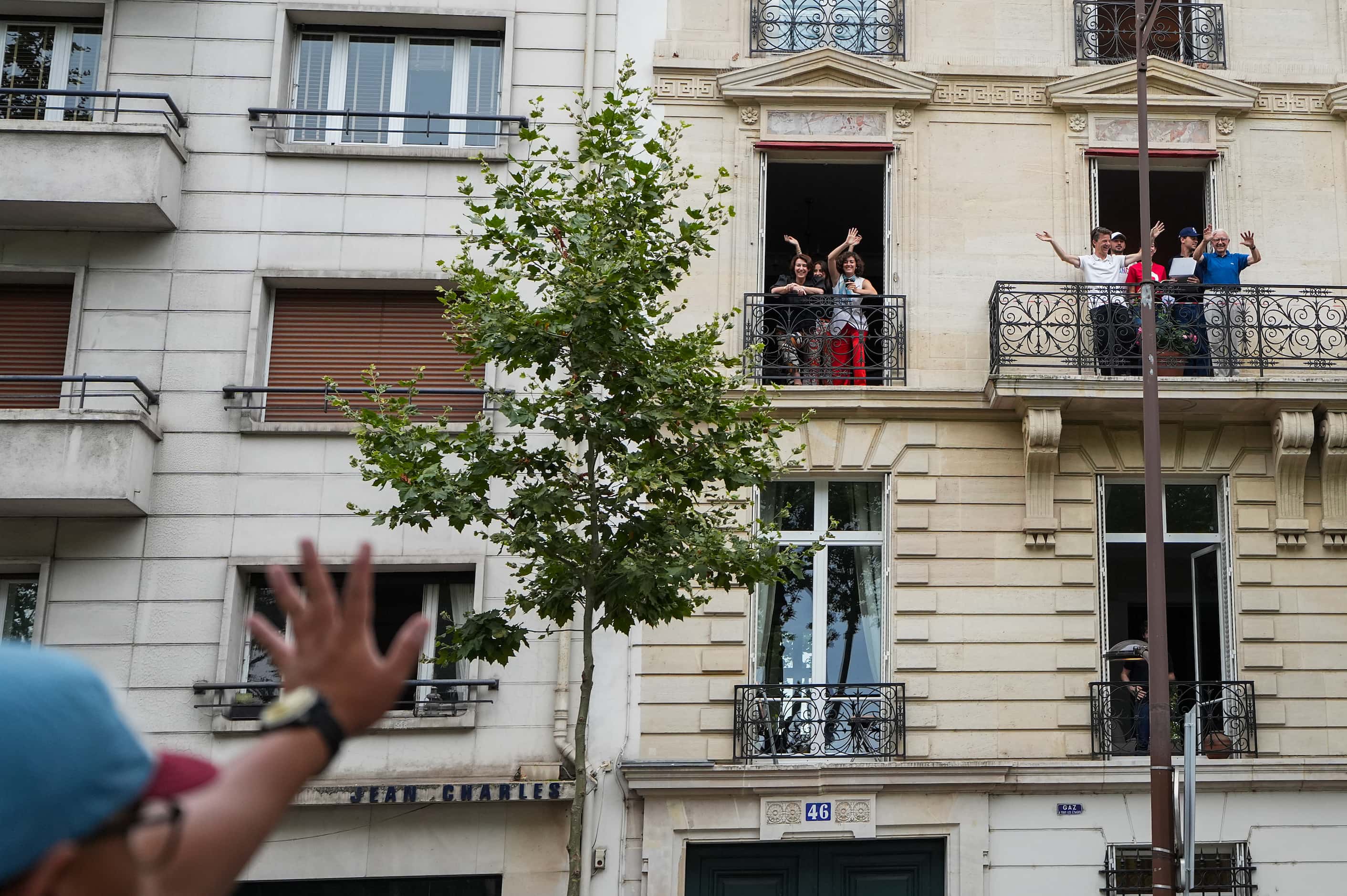 People wave from balconies while waiting for the opening ceremonies for the 2024 Summer...