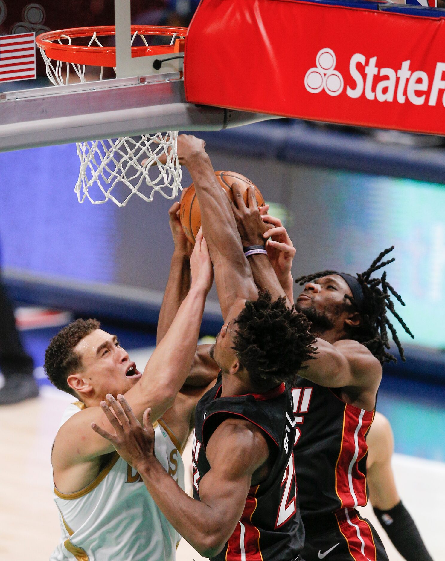 Dallas Mavericks forward Dwight Powell, left, battles Miami Heat forwards Jimmy Butler, and...