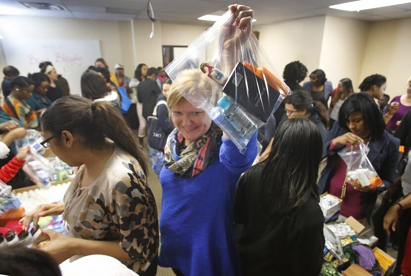 
Stephanie Cole passes along a gift bag as volunteers make them for clients at Genesis...