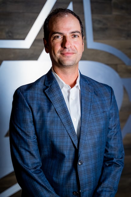 Al Montoya poses for a headshot with the Dallas Stars logo in the background.