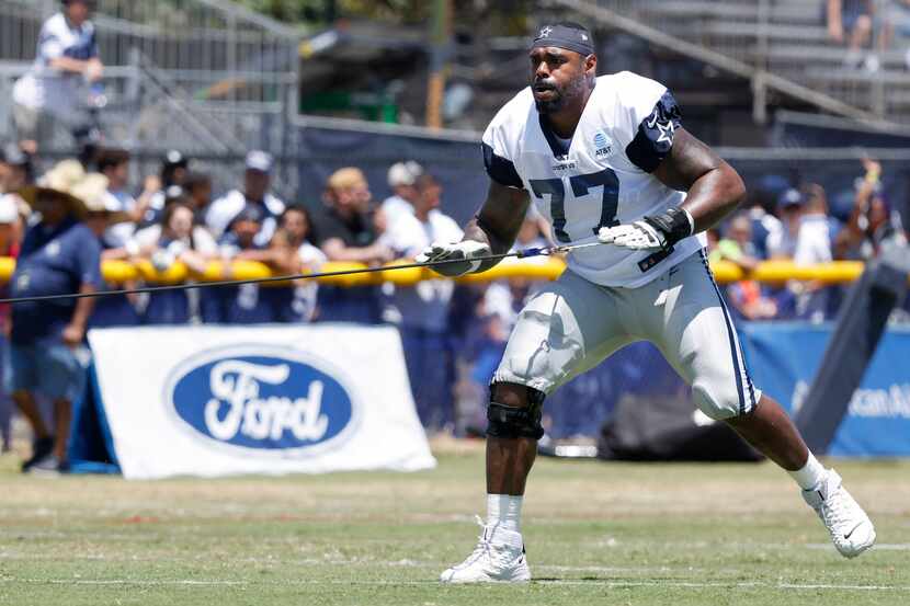 Dallas Cowboys offensive tackle Tyron Smith (77) uses a resistance cord at the end of...