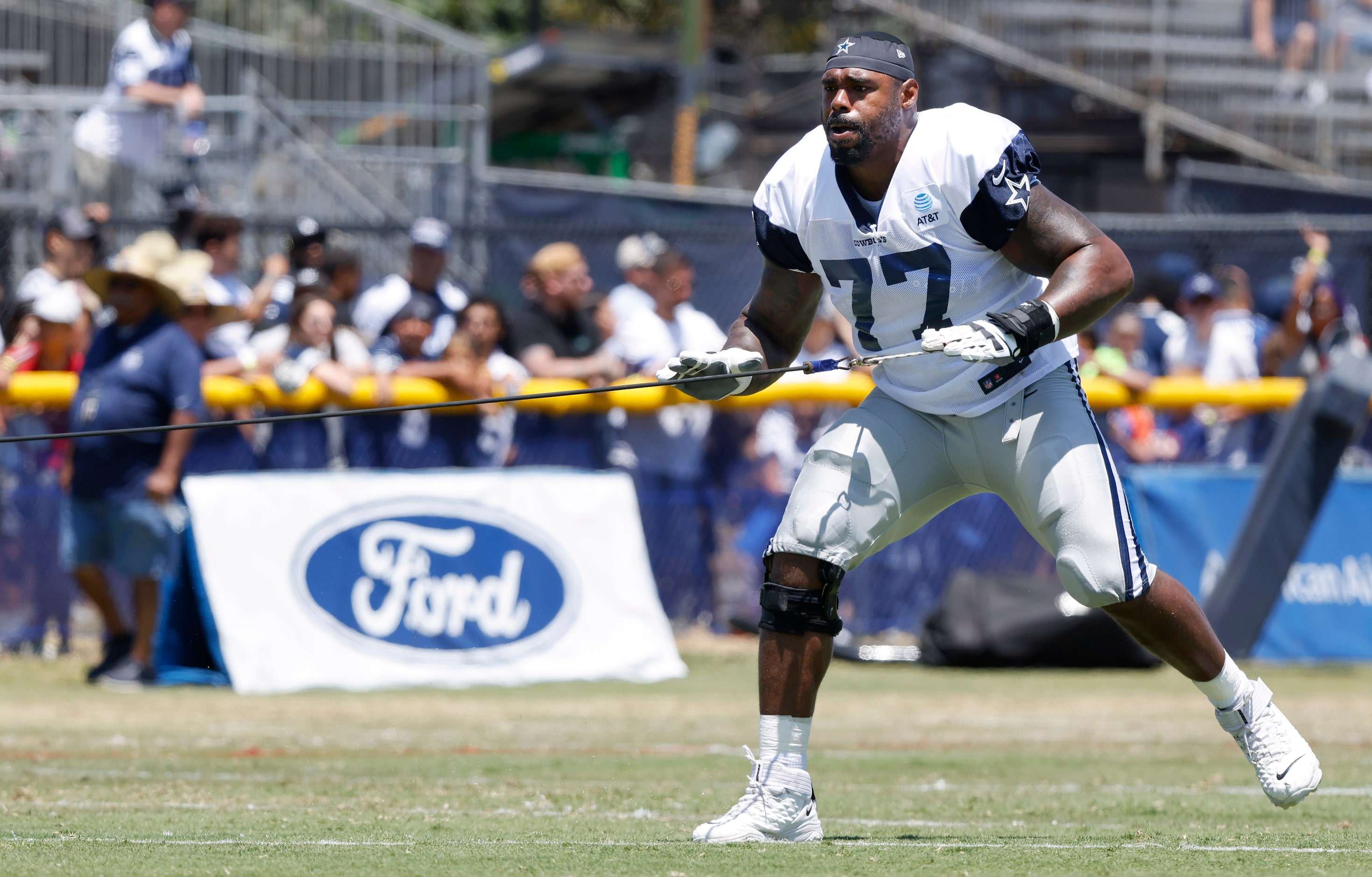 Dallas Cowboys offensive tackle Tyron Smith (77) uses a resistance cord at the end of...