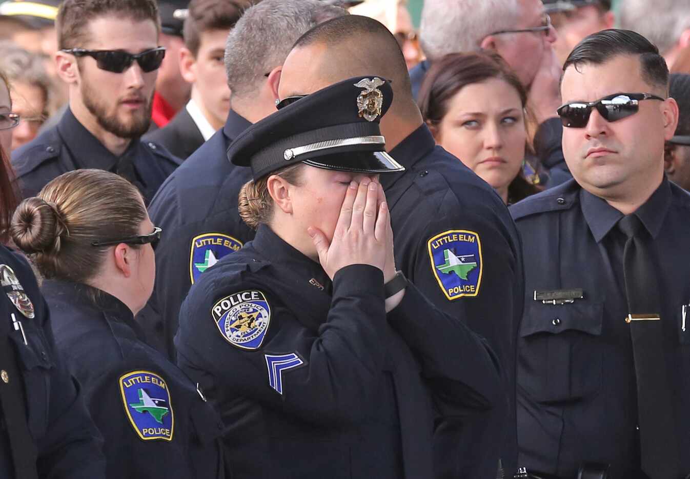 A Frisco police officer wipes away tears at the funeral service for Little Elm Police...