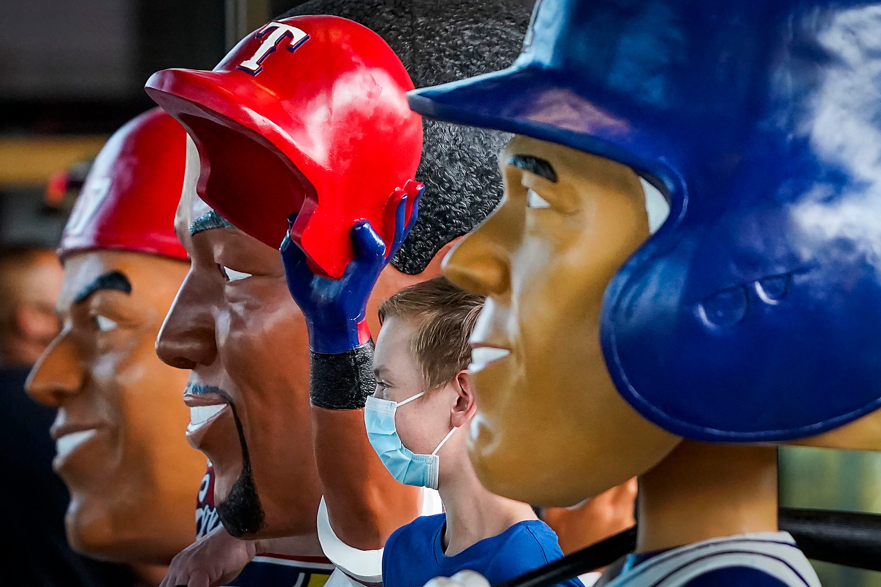 Fan Traevyn Cook, 14, from Oklahoma, poses for a photo between bobble head statues of Texas...