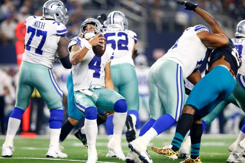 Dallas Cowboys quarterback Dak Prescott (4) spins away from a possible sack and rolls out to...