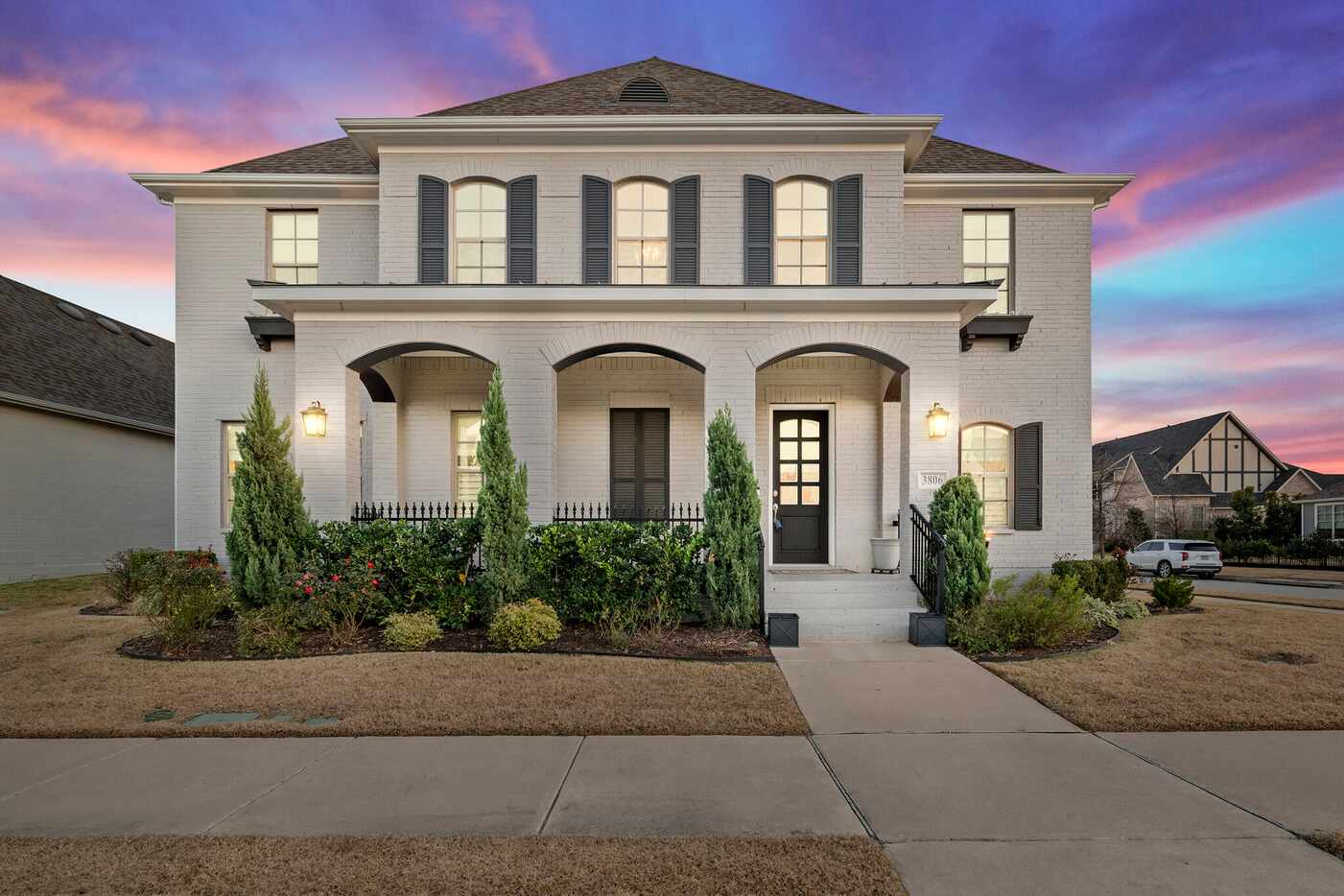 The exterior of the home features white painted brick and many windows.