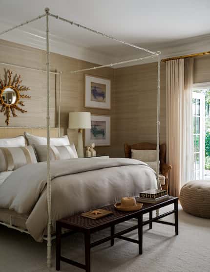 Bedroom with neutral, pale beige hues with four-poster bed, mirror above the bed and bench...