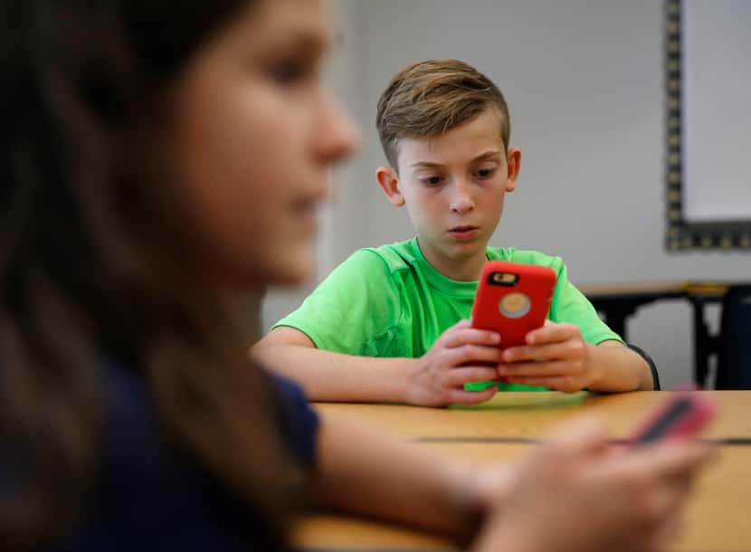 Sixth-graders Brock Benner (right), 11, and Lauren Bazan (foreground left), 11, look for the...