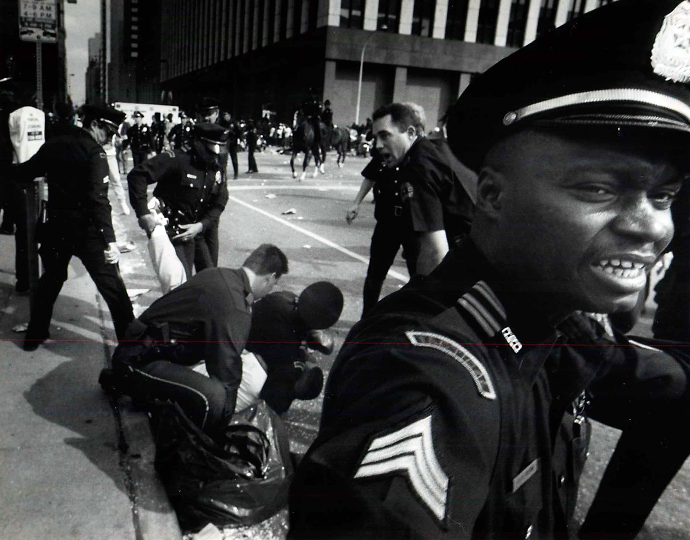 Dallas police SWAT Sgt. David Brown (right) keeps bystanders back as colleagues restrain a...