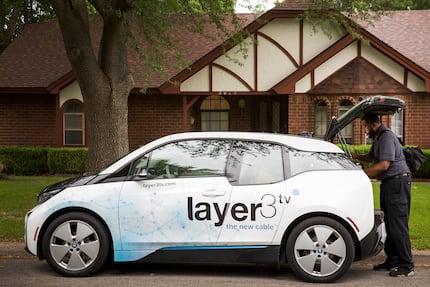 Keith Hamilton of Layer3 grabs gear from his car, a BMW i3, as he installs cable TV...