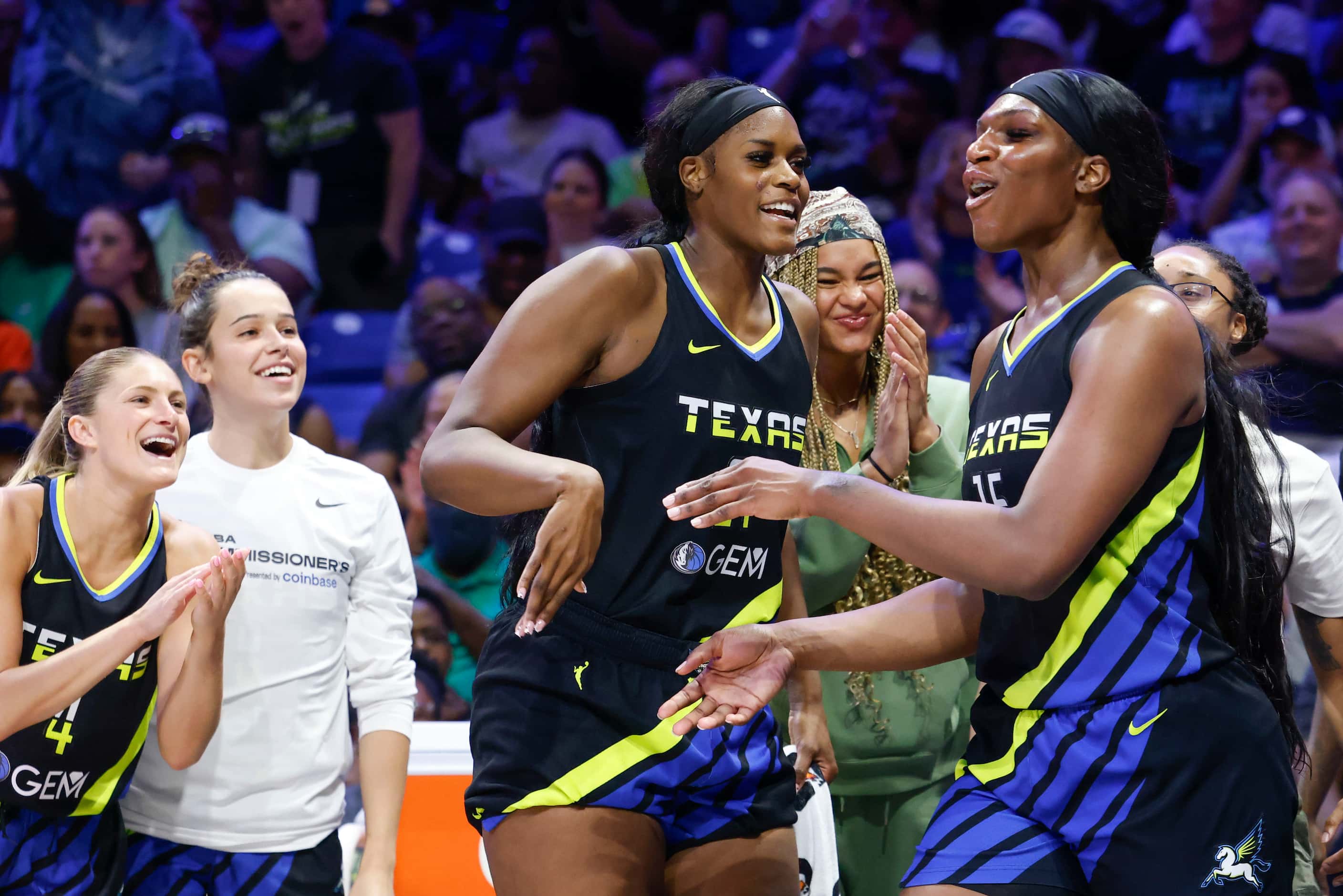 Dallas Wings center Teaira McCowan (right) cheers with her teammates after blocking a shot...