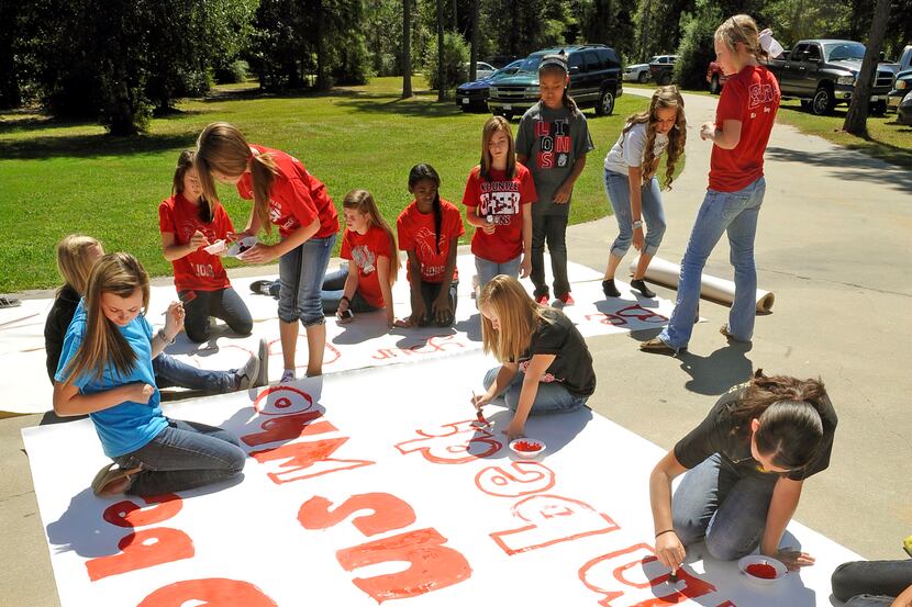 Kountze High School cheerleaders and other children worked on a large sign Wednesday in the...