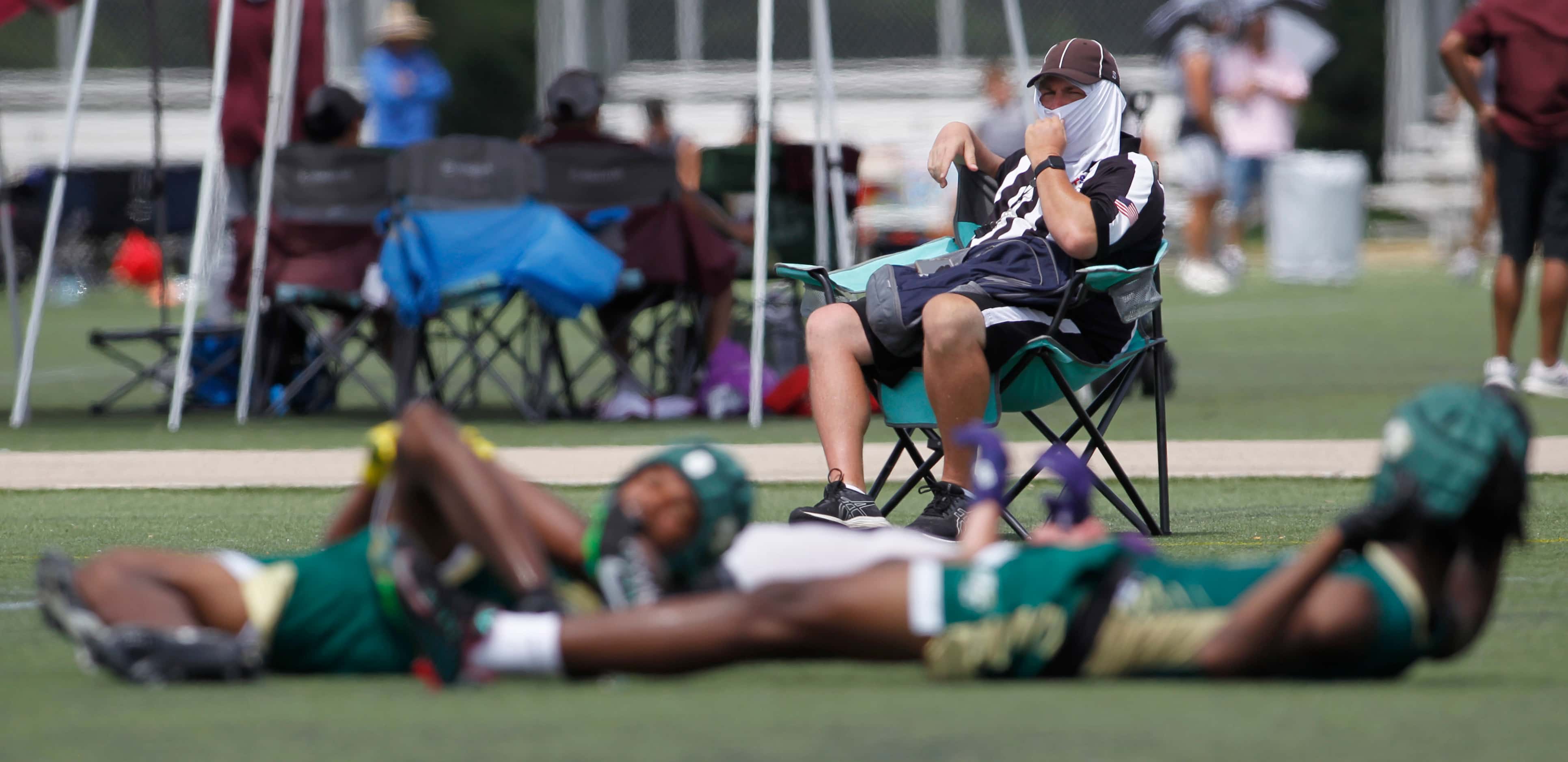 A game official on break looks on as two DeSoto defenders and an Anna receiver collided in...