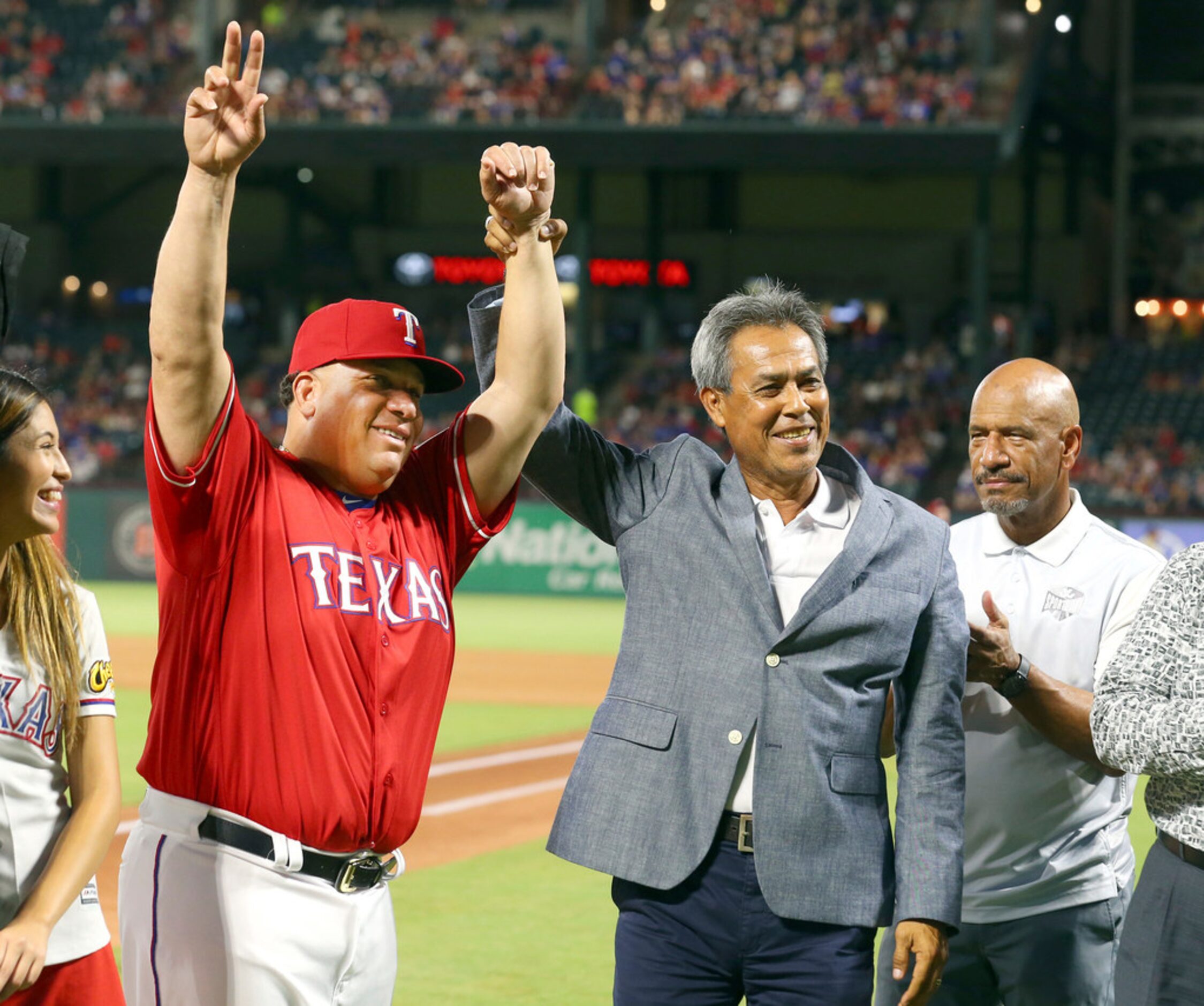 Texas Rangers pitcher Bartolo Colon raises his arms next to former pitcher Dennis Martinez...