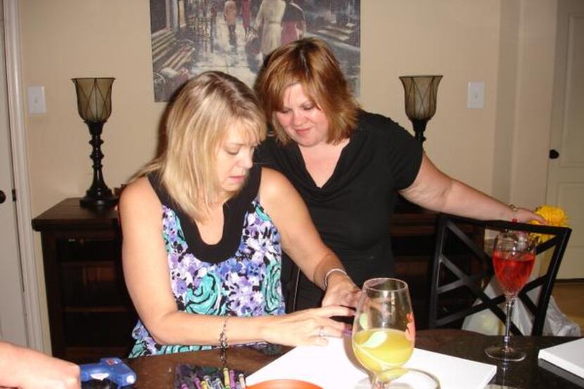 Stephanie Hill (left) and Cher Ewing glue crayons to a canvas as part of a series of...