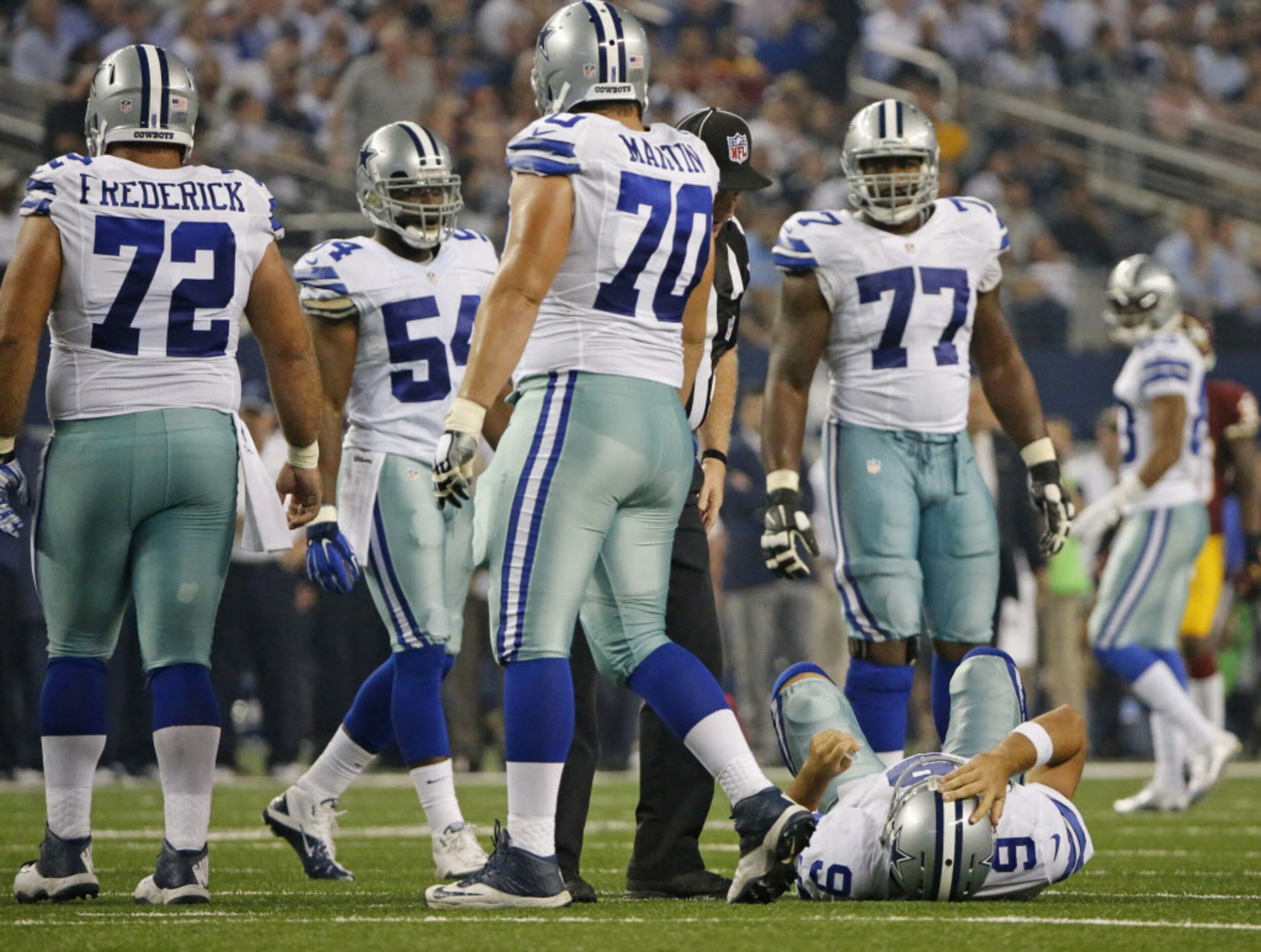 Dallas Cowboys quarterback Tony Romo (9) lies on the ground after being crunched by...