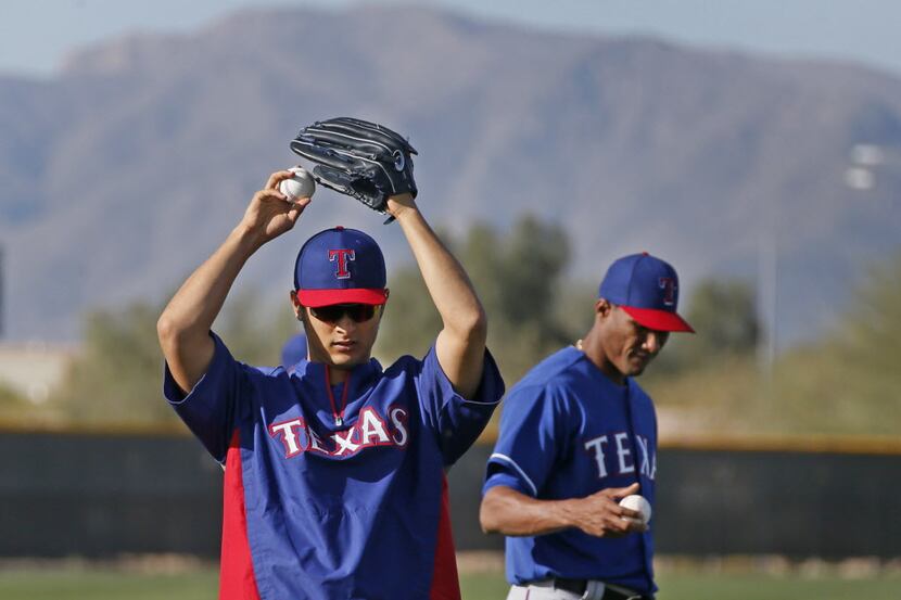 Texas pitchers Yu Darvish and Alexi Ogando loosen up during Texas Rangers baseball spring...