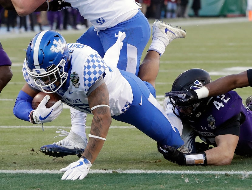 Kentucky running back Benny Snell Jr., left, gets past Northwestern defender Paddy Fisher...