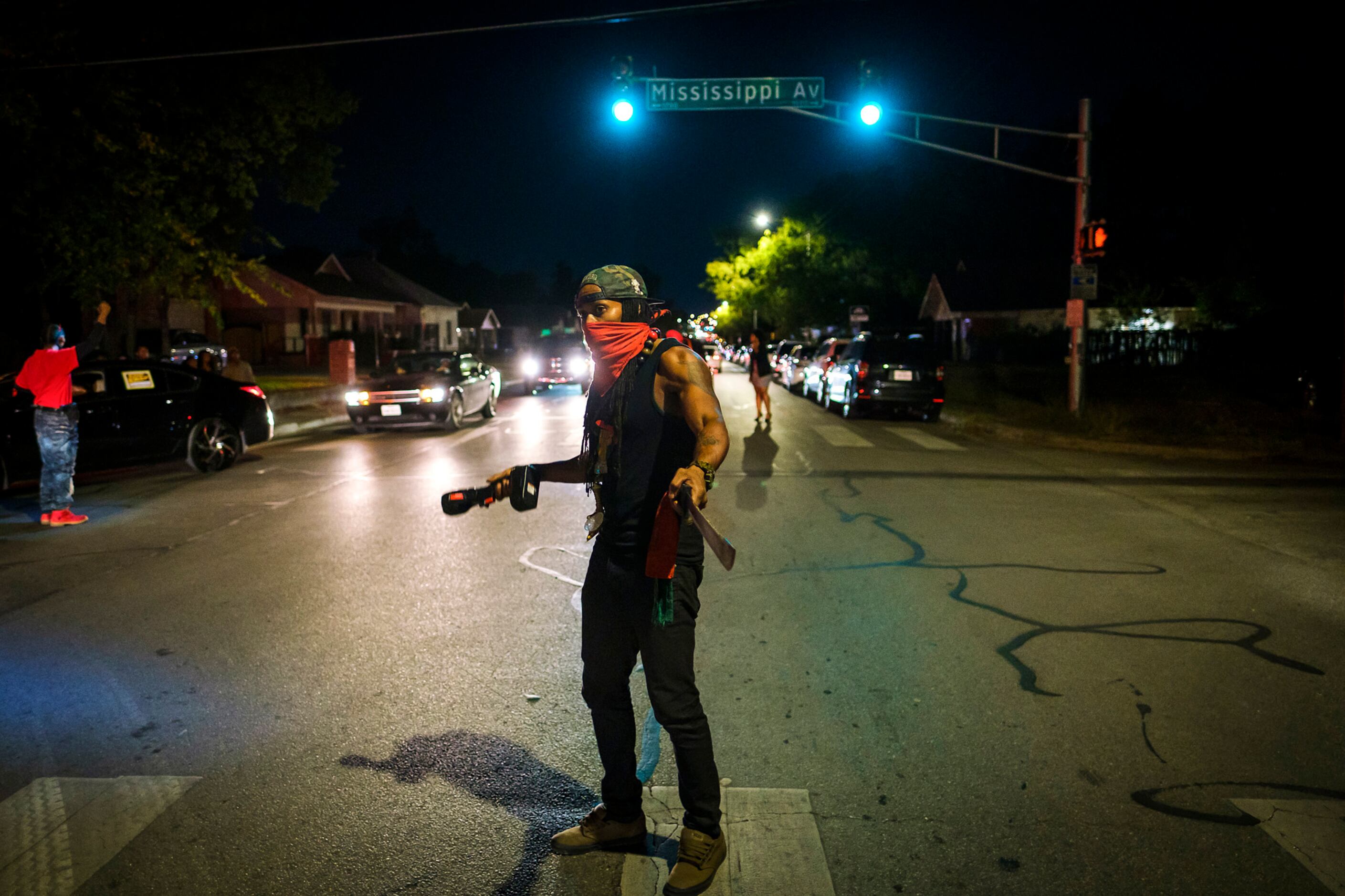 A masked man man carrying a machete directs traffic in 1200 block of East Allen Avenue...