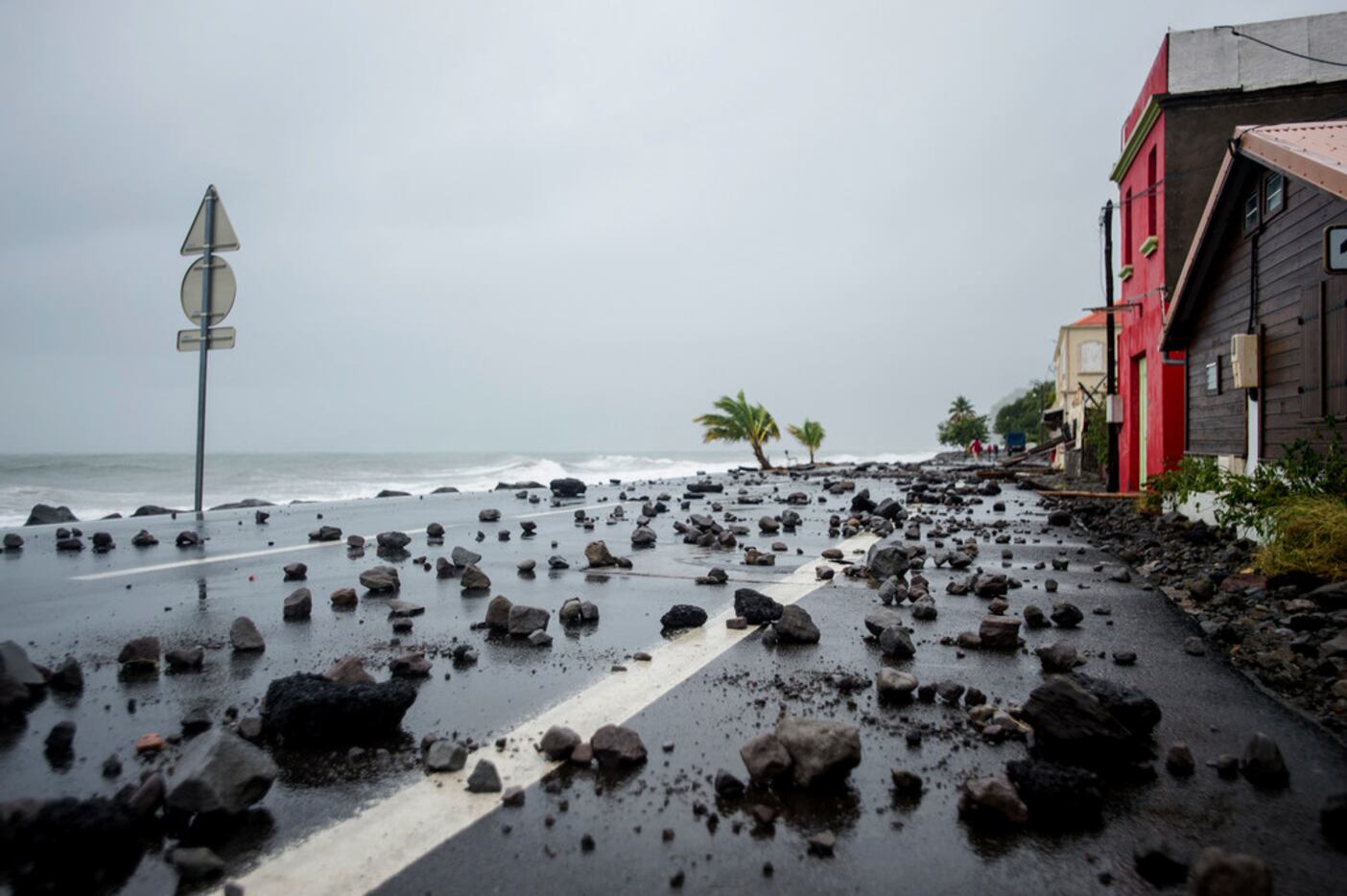 A picture shows rocks swept by strong waves onto a road in Le Carbet, on the French...