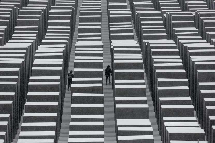 Visitors walk explore the snow-covered Holocaust Memorial at the International Holocaust...