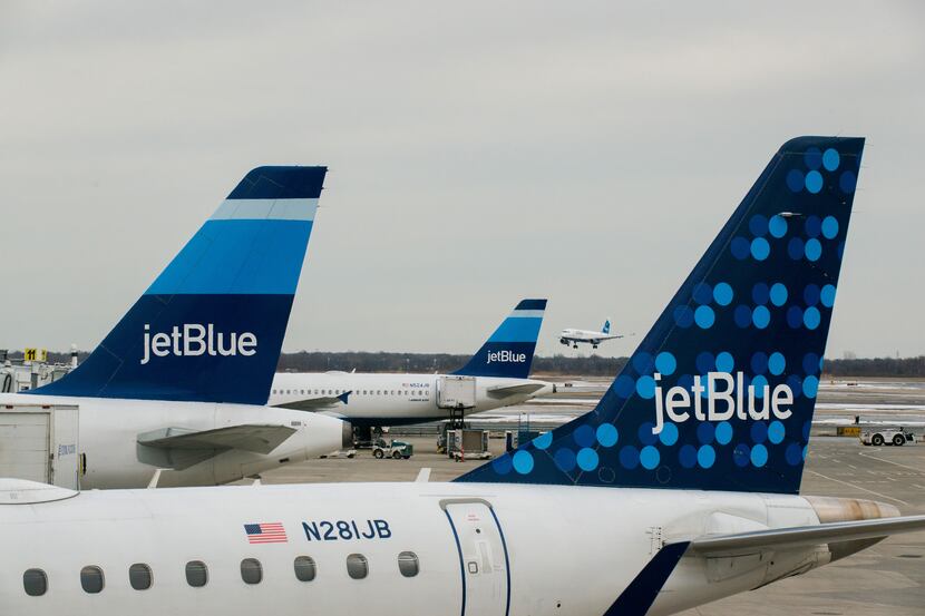 JetBlue Airways Corp. planes sit docked at the gates of Terminal 5 as another of the...