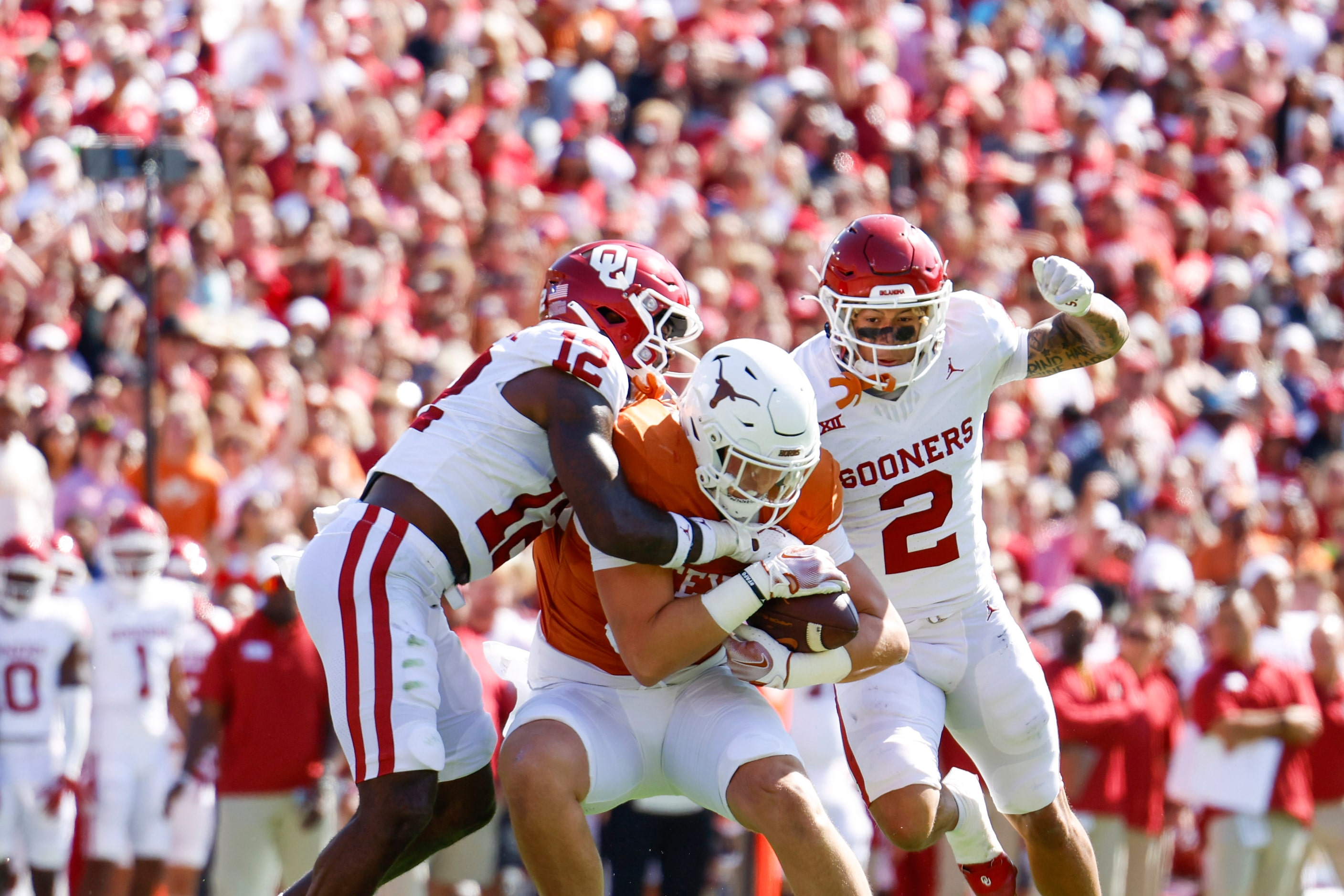 Oklahoma defensive back Key Lawrence (left) tackles Texas tight end Gunnar Helm (center)...