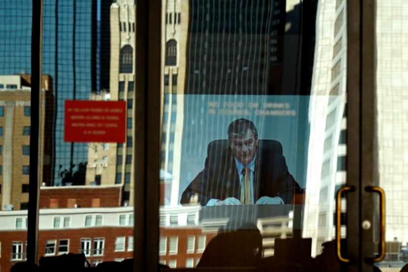  Dallas Mayor Mike Rawlings opens up the city council meeting in the reflection of the outer...