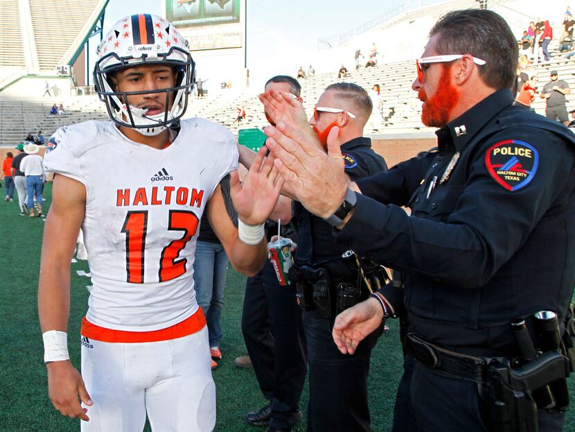 Haltom High School quarterback Michael Black (12) is congratulated by a Haltom City police...