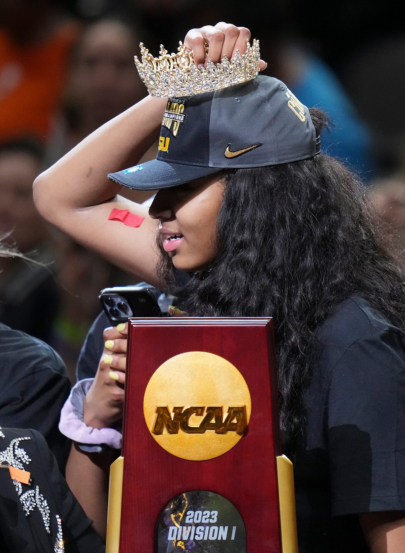 LSU forward Angel Reese holds a crown over her head while celebrating with the trophy after...