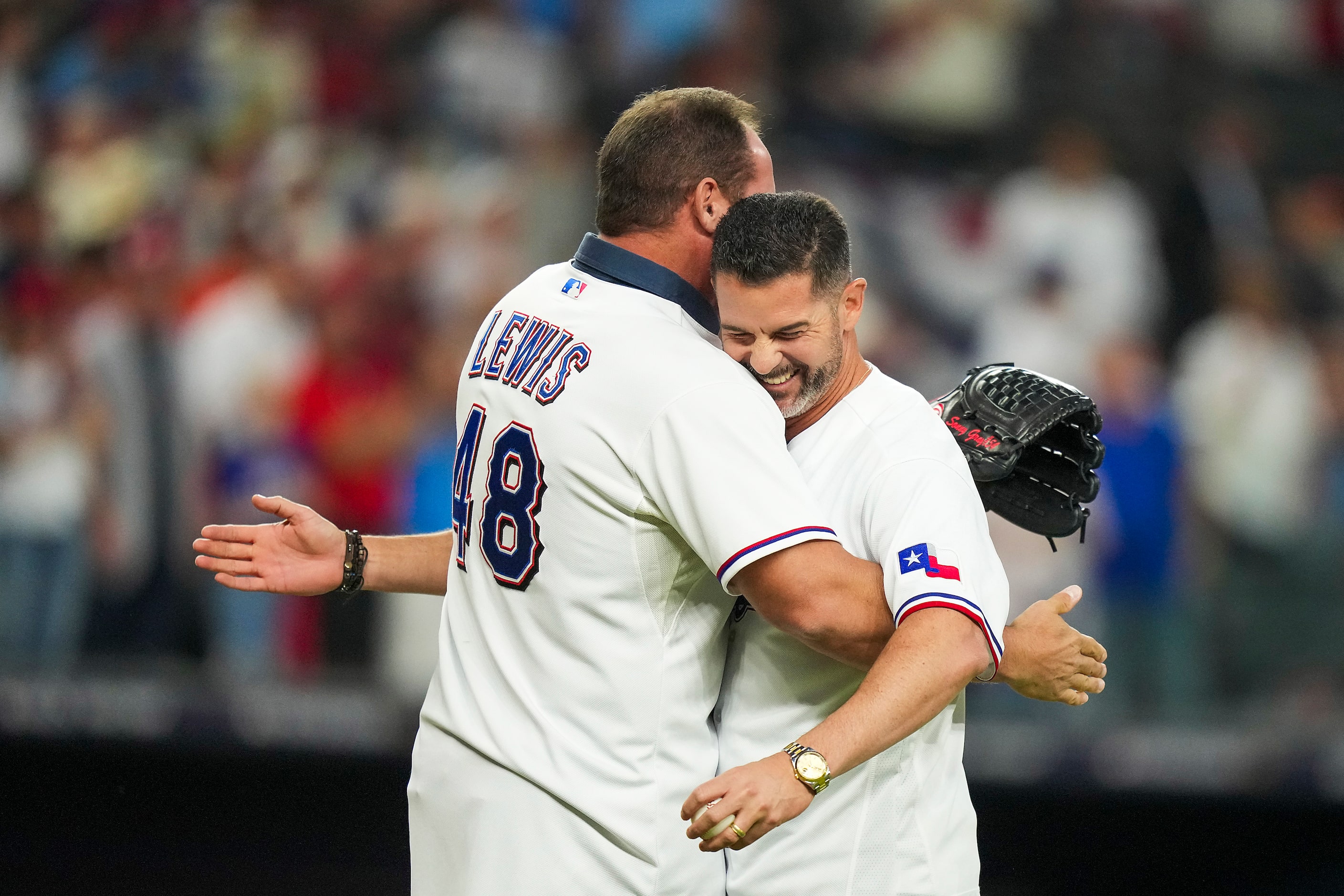 Former Texas Rangers Michael Young hugs Colby Lewis after throwing a ceremonial first pitch...