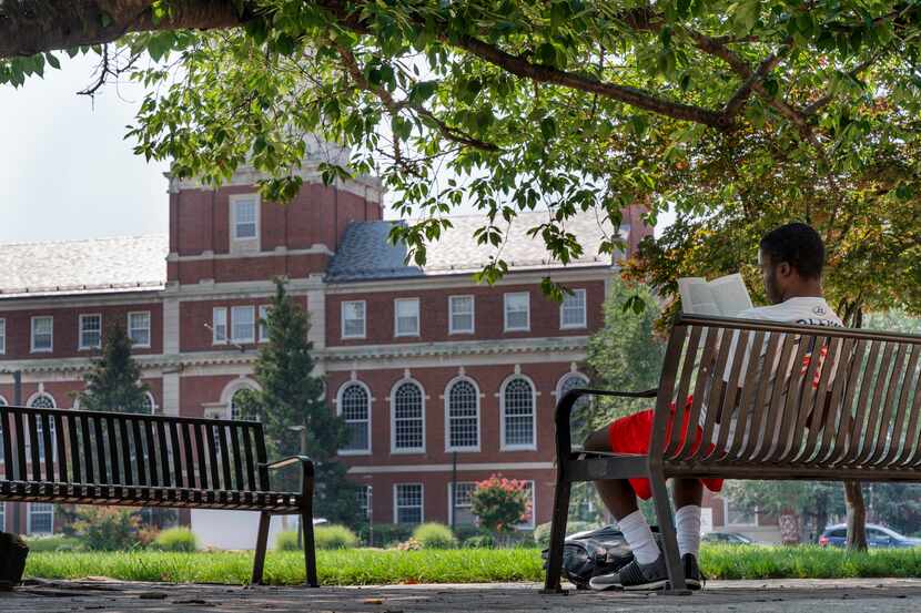With the Founders Library in the background, a young man reads on Howard University campus...